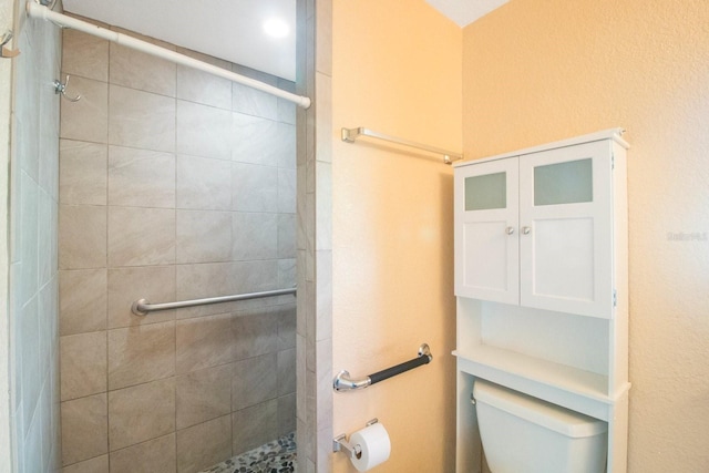 bathroom featuring a tile shower and toilet