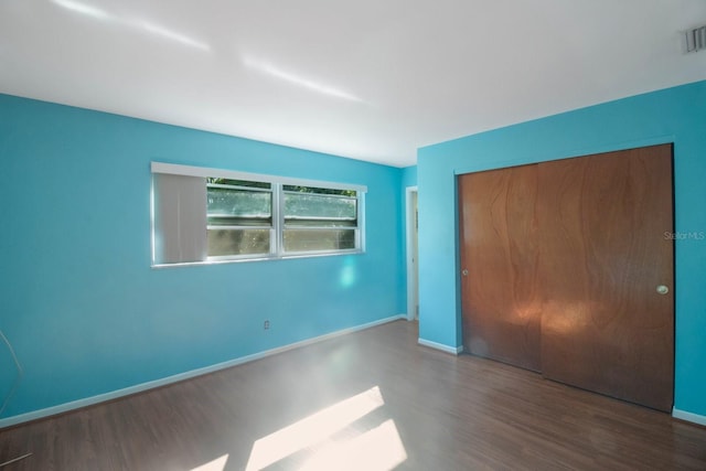 unfurnished bedroom with dark wood-type flooring and a closet