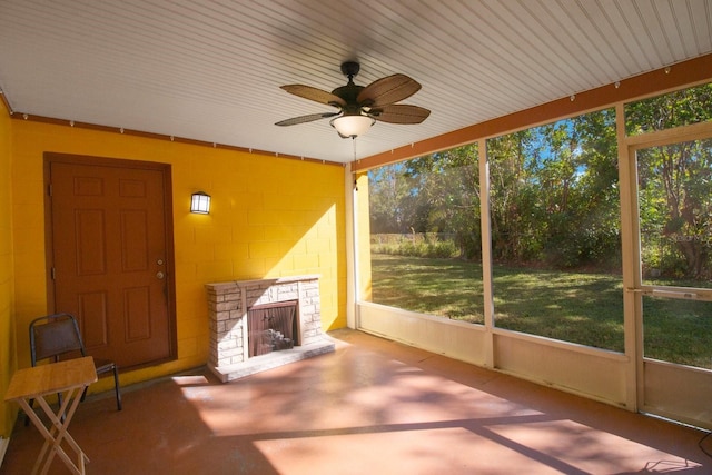 unfurnished sunroom featuring plenty of natural light, ceiling fan, and a fireplace