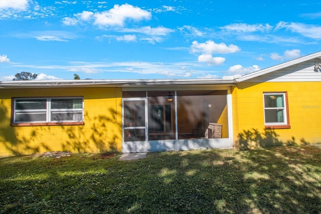 back of property with a sunroom and a yard