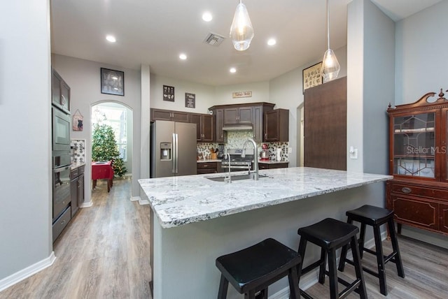 kitchen featuring appliances with stainless steel finishes, backsplash, sink, decorative light fixtures, and light hardwood / wood-style flooring