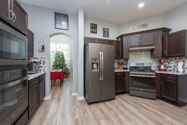 kitchen featuring dark brown cabinetry, stainless steel appliances, light hardwood / wood-style floors, and backsplash