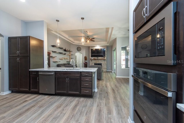 kitchen featuring a raised ceiling, light hardwood / wood-style flooring, ceiling fan, dark brown cabinetry, and stainless steel appliances