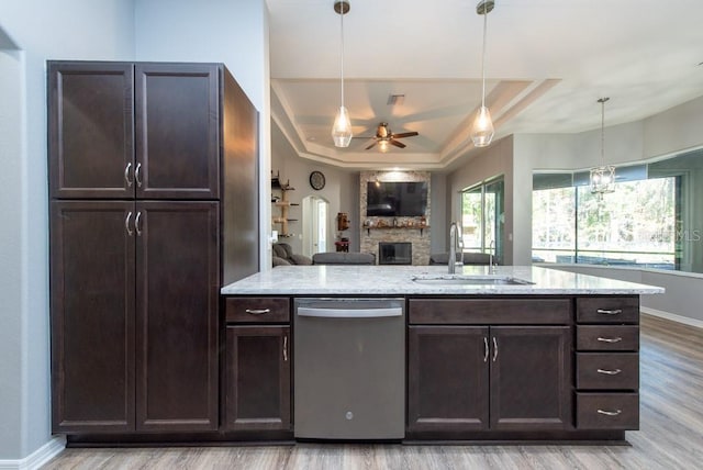 kitchen with light wood-type flooring, a tray ceiling, sink, dishwasher, and hanging light fixtures