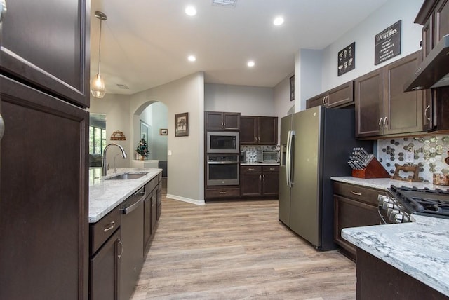 kitchen featuring decorative backsplash, appliances with stainless steel finishes, sink, pendant lighting, and light hardwood / wood-style flooring