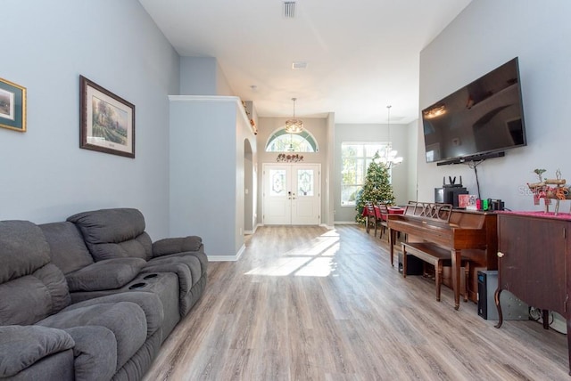 living room with french doors, light wood-type flooring, and a notable chandelier