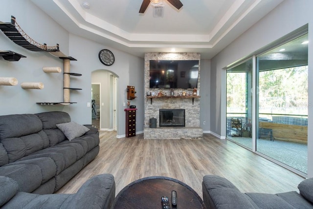 living room featuring a raised ceiling, ceiling fan, a fireplace, and hardwood / wood-style flooring