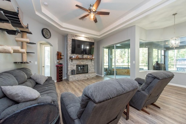 living room featuring a healthy amount of sunlight, a raised ceiling, and light hardwood / wood-style flooring