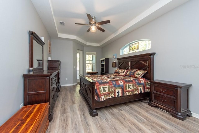 bedroom featuring a tray ceiling, ceiling fan, and light hardwood / wood-style flooring