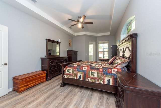 bedroom featuring a raised ceiling, ceiling fan, and light hardwood / wood-style floors