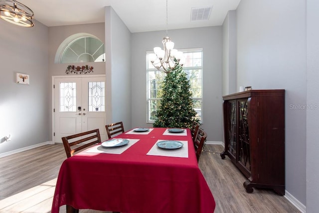 dining space with a chandelier, french doors, and light hardwood / wood-style floors