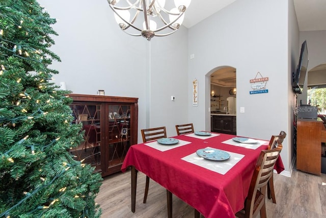 dining space featuring hardwood / wood-style flooring, high vaulted ceiling, and an inviting chandelier