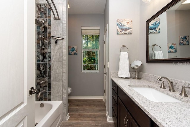 full bathroom with vanity, hardwood / wood-style flooring, toilet, and tiled shower / bath combo