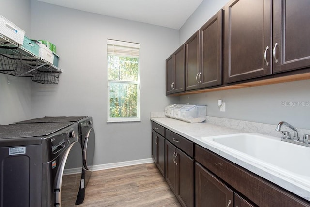 laundry room featuring light hardwood / wood-style floors, cabinets, sink, and washing machine and dryer