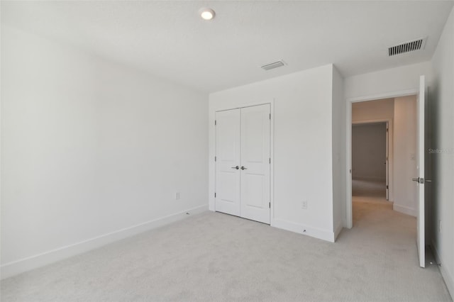 unfurnished bedroom featuring light carpet and a closet