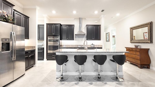 kitchen with a kitchen island with sink, sink, wall chimney range hood, and appliances with stainless steel finishes