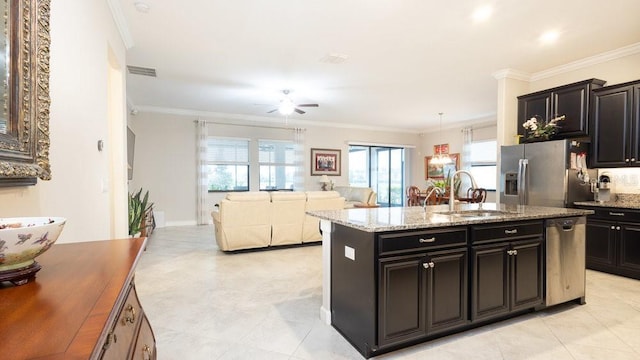 kitchen with appliances with stainless steel finishes, ornamental molding, ceiling fan, sink, and a center island with sink