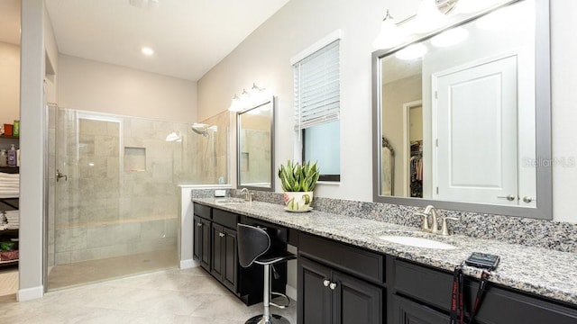 bathroom with tile patterned flooring, vanity, and tiled shower