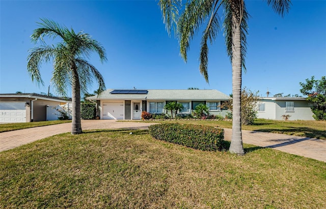 ranch-style home featuring a front yard, solar panels, and a garage