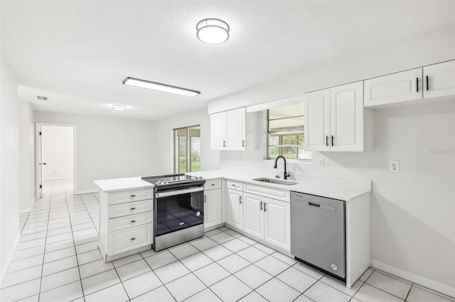 kitchen featuring kitchen peninsula, appliances with stainless steel finishes, sink, white cabinetry, and light tile patterned flooring