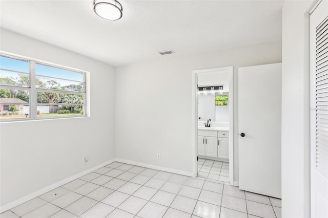 unfurnished room with a textured ceiling, light tile patterned floors, and sink