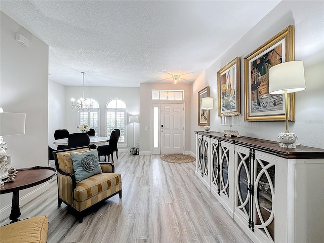 foyer entrance with hardwood / wood-style flooring, a textured ceiling, and a chandelier