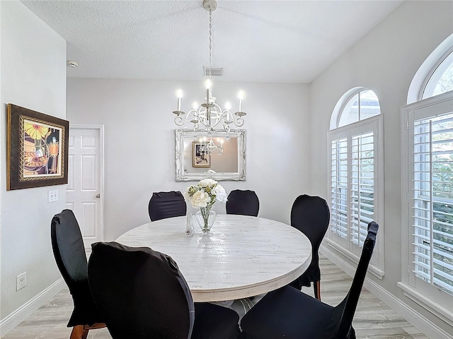 dining room with a textured ceiling, light wood-type flooring, and a notable chandelier