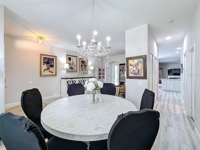 dining room with a chandelier, a textured ceiling, and light hardwood / wood-style flooring