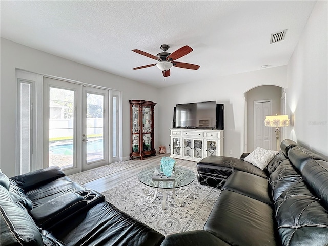 living room featuring french doors, a textured ceiling, hardwood / wood-style flooring, and ceiling fan