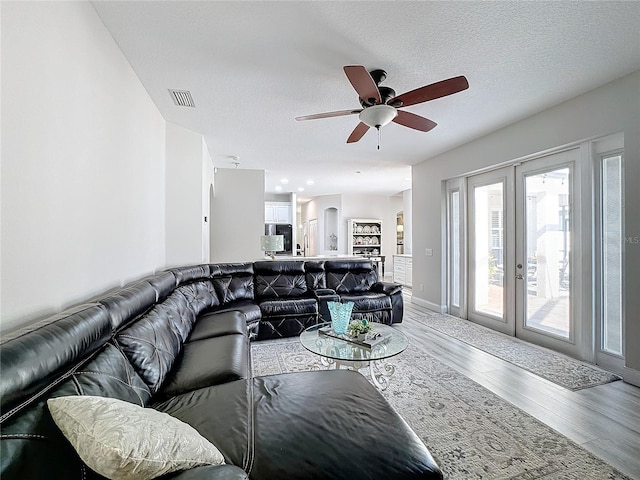 living room featuring ceiling fan, french doors, a textured ceiling, and hardwood / wood-style flooring