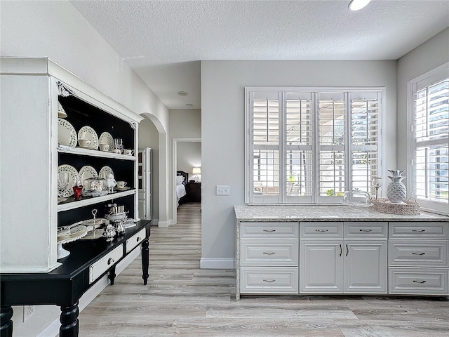 kitchen with white cabinetry, a textured ceiling, and light hardwood / wood-style flooring