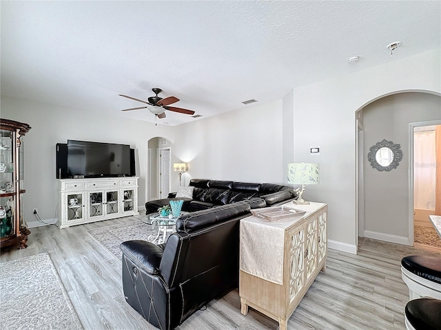 living room featuring a textured ceiling, light hardwood / wood-style floors, and ceiling fan