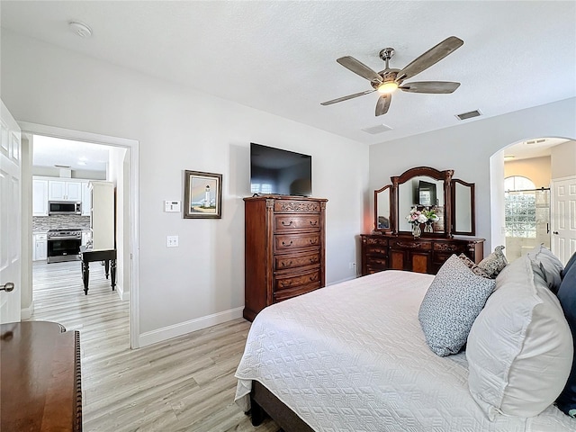 bedroom featuring ceiling fan, connected bathroom, and light hardwood / wood-style flooring