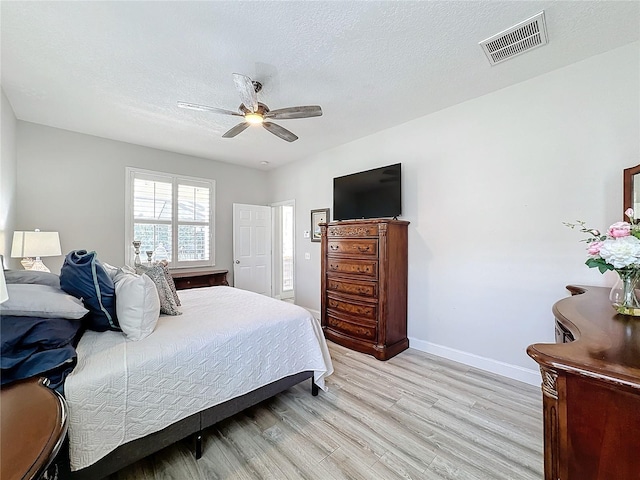 bedroom with ceiling fan, light hardwood / wood-style floors, and a textured ceiling