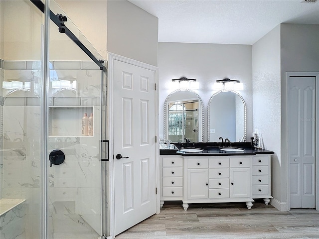 bathroom with a shower with door, vanity, a textured ceiling, and hardwood / wood-style flooring