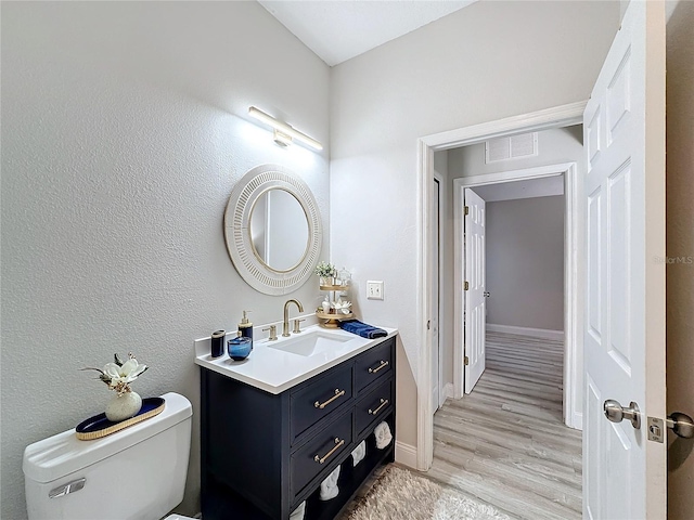 bathroom with hardwood / wood-style floors, vanity, and toilet