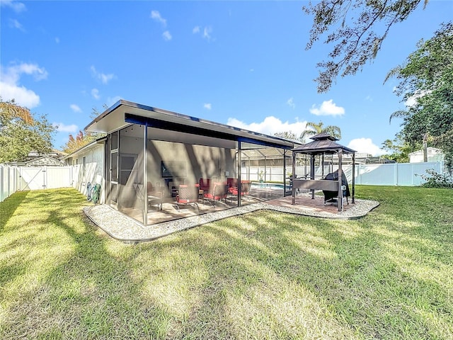 rear view of property with a gazebo, a patio area, a lawn, and a lanai