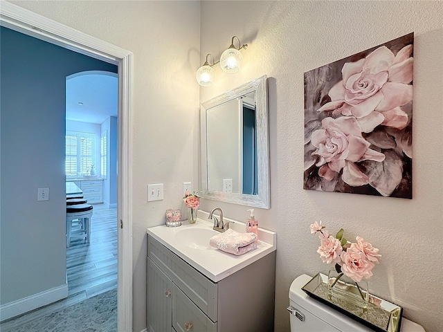 bathroom featuring vanity, wood-type flooring, and toilet