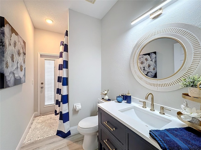 bathroom featuring vanity, wood-type flooring, a textured ceiling, and toilet