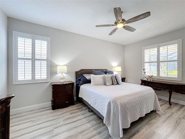 bedroom with ceiling fan, light hardwood / wood-style floors, and a textured ceiling