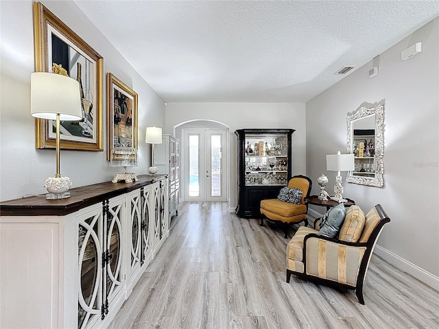 entryway with french doors, a textured ceiling, and light hardwood / wood-style floors