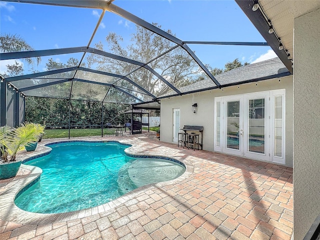 view of pool with exterior bar, french doors, a lanai, and a patio area