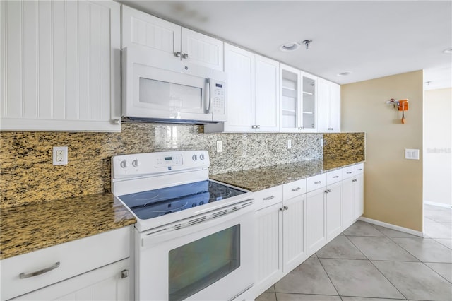 kitchen with white cabinetry, tasteful backsplash, dark stone countertops, white appliances, and light tile patterned flooring