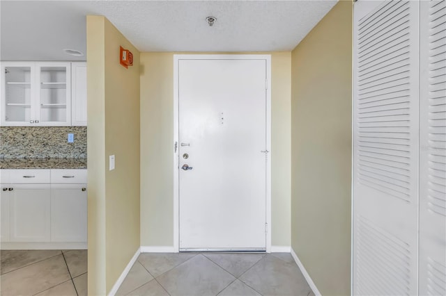 entryway featuring light tile patterned floors and a textured ceiling