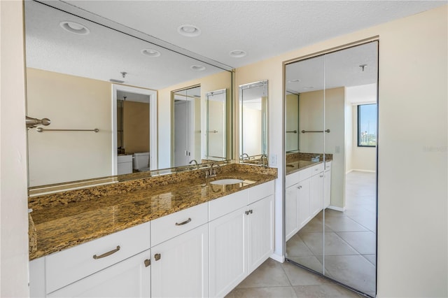 bathroom with tile patterned flooring, a textured ceiling, vanity, and toilet