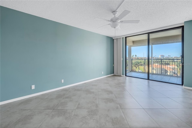 unfurnished room featuring ceiling fan, expansive windows, and a textured ceiling