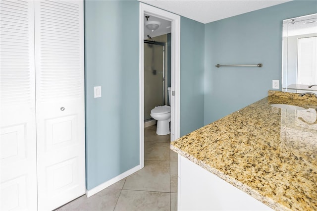 bathroom featuring toilet, vanity, tile patterned floors, and a shower with door