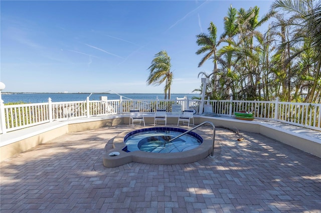 view of pool with an in ground hot tub, a water view, and a patio area