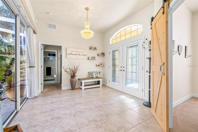 tiled foyer entrance featuring a barn door and french doors