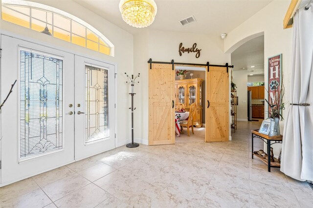 foyer with french doors, tile patterned floors, vaulted ceiling, a barn door, and an inviting chandelier